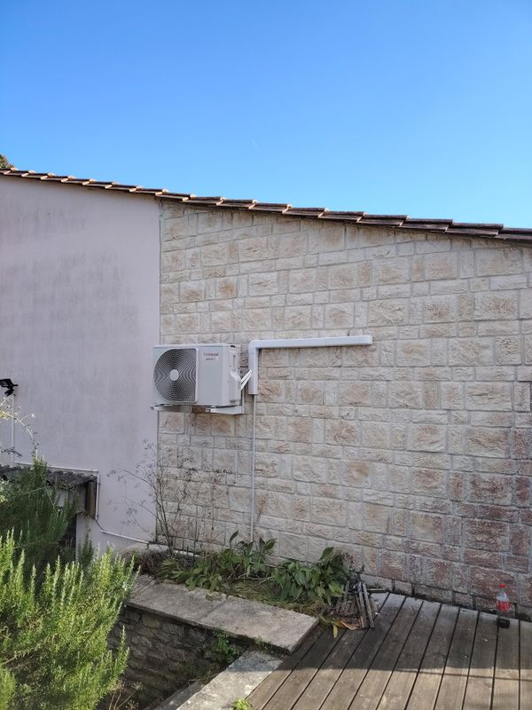 Installation climatisation unité extérieure pompe à chaleur sur façade maison